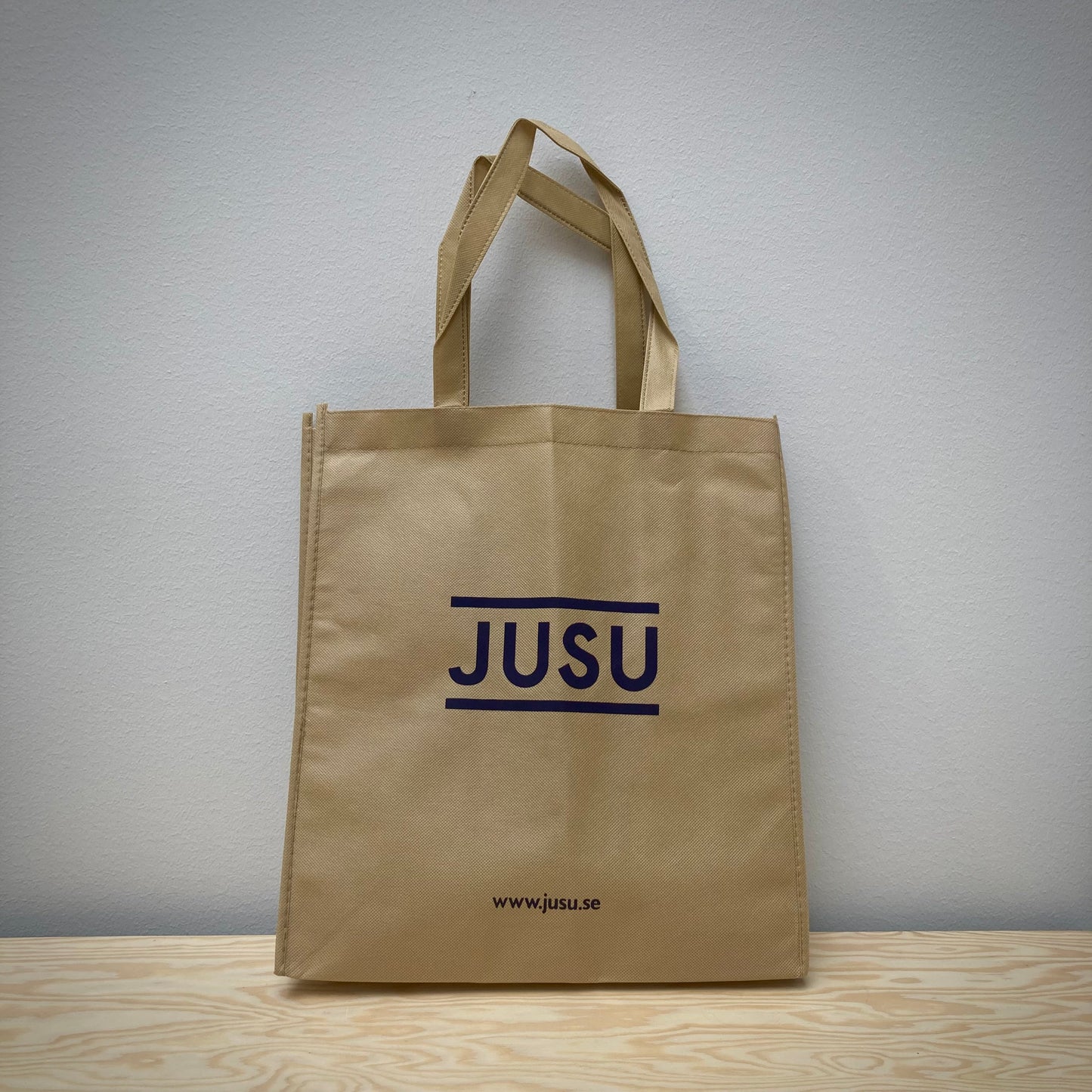 Beige påse med JUSU-tryck